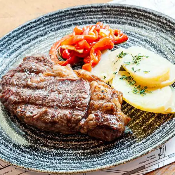 Grilled beef entrecôte with sliced potatoes and confit red peppers