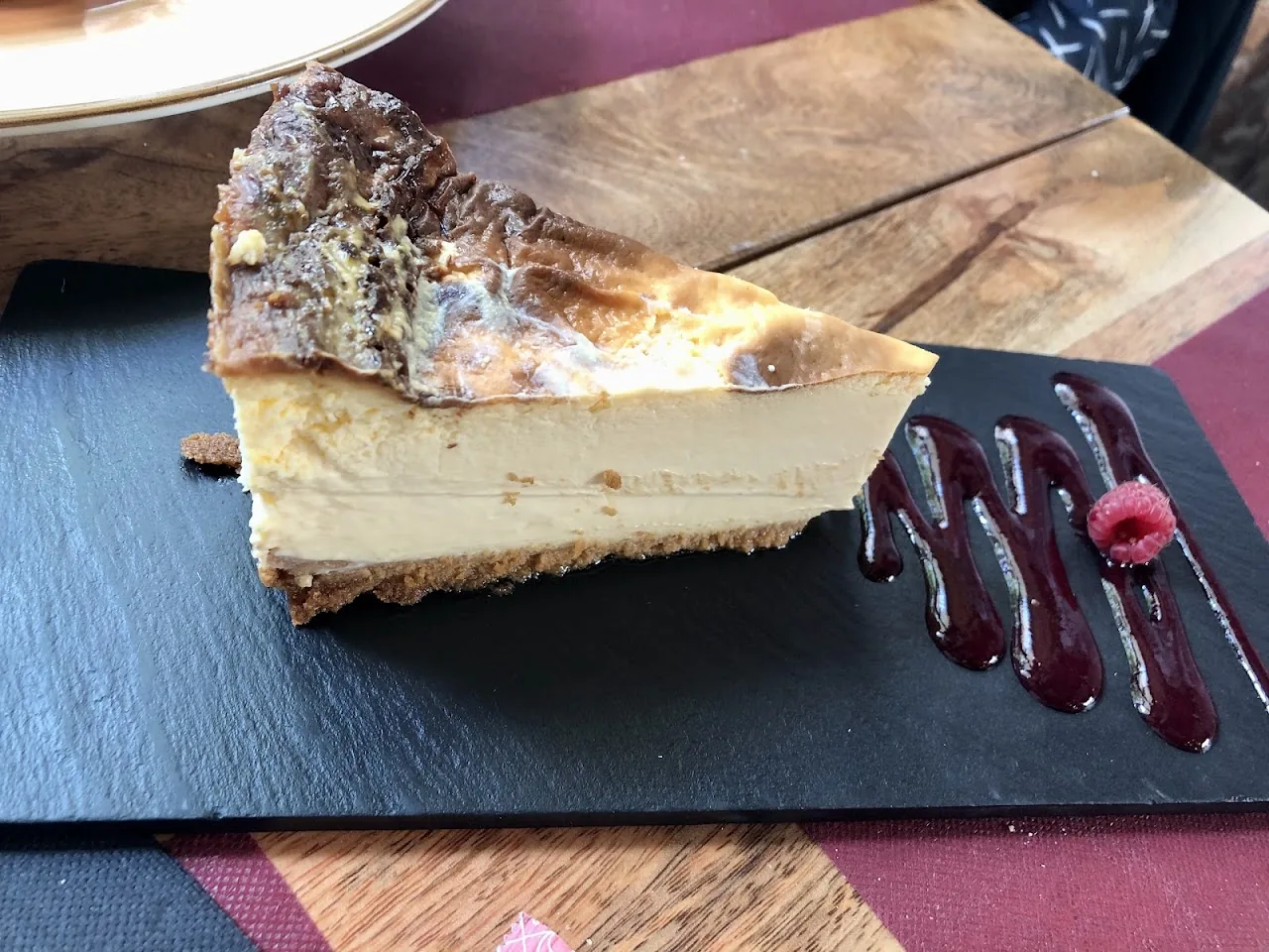 A slice of cheesecake with a berry compote drizzle
