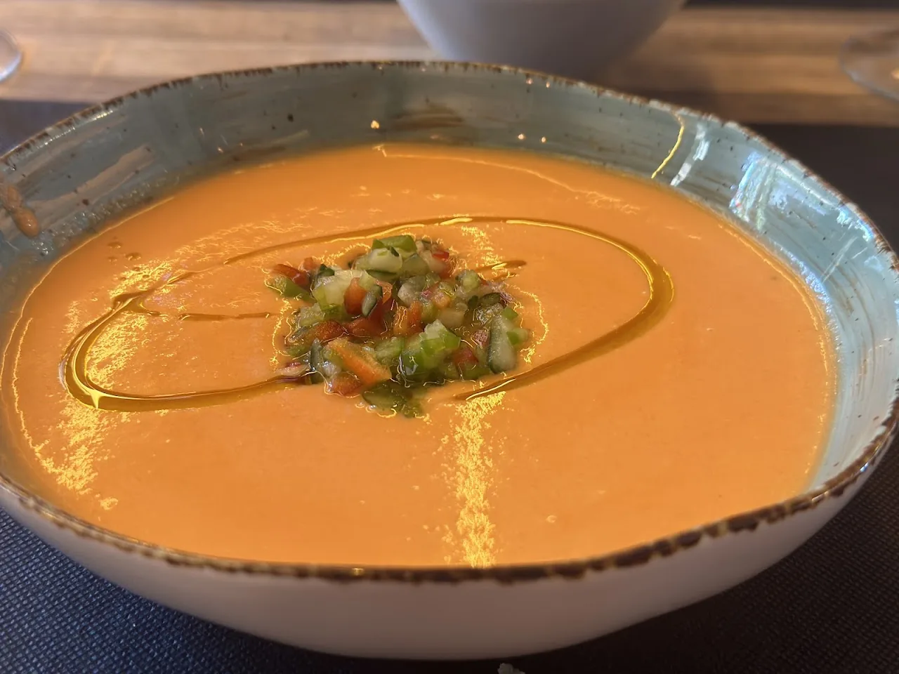 A bowl of gazpacho garnished with diced vegetables and olive oil