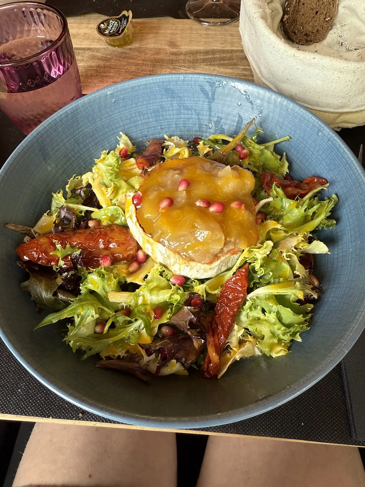 A green salad topped with burrata and pomegranate seeds