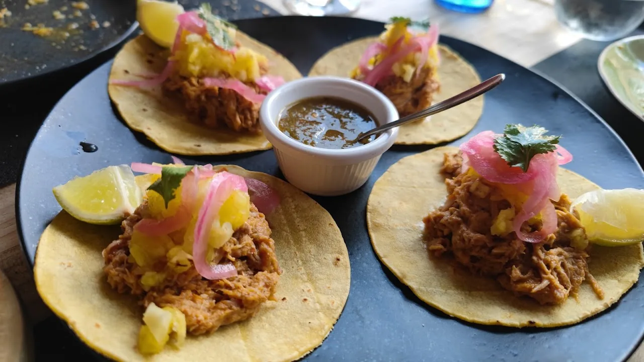 Three tacos filled with pulled meat and pineapple