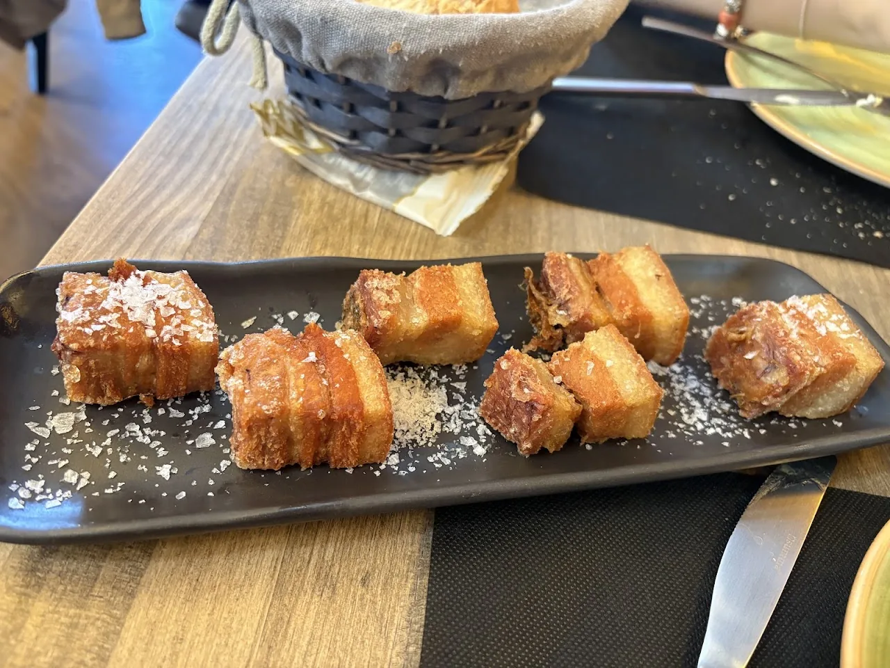 Crispy pork belly bites on a slate board