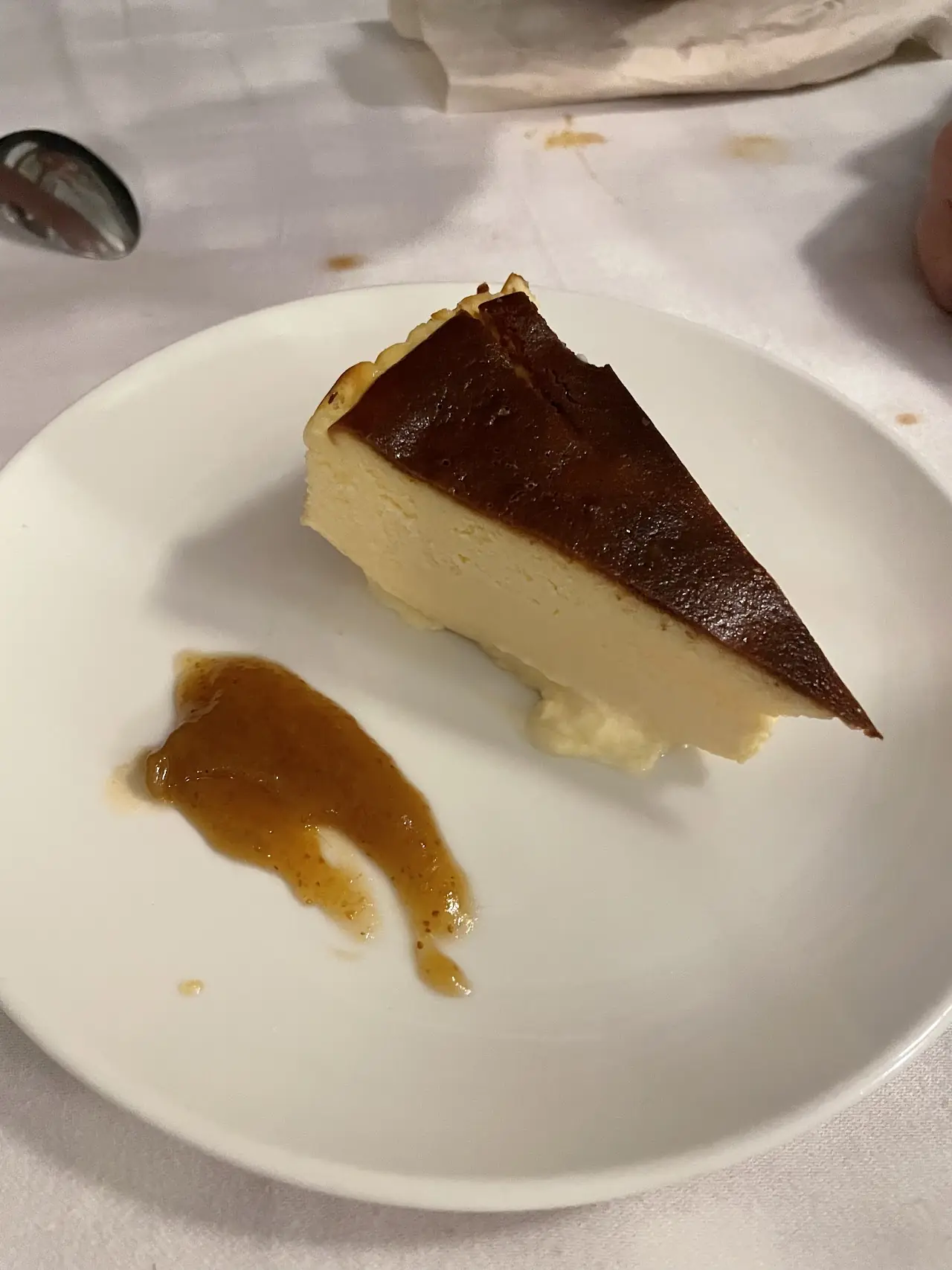 Slice of baked cheesecake with a swirl of caramel sauce on the plate