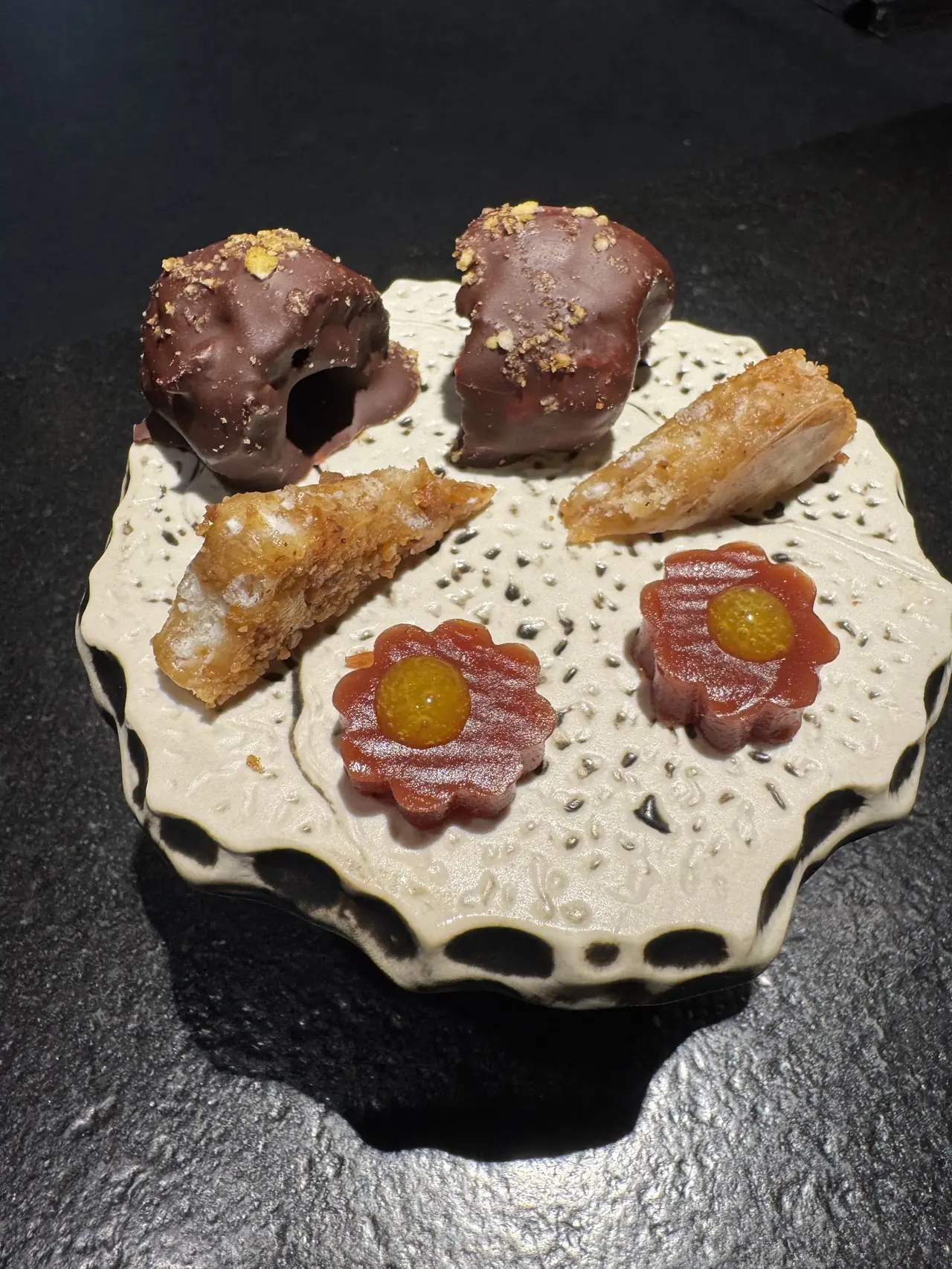 Small plate of chocolate-coated bites, pastry rolls, and flower-shaped jelly canapes