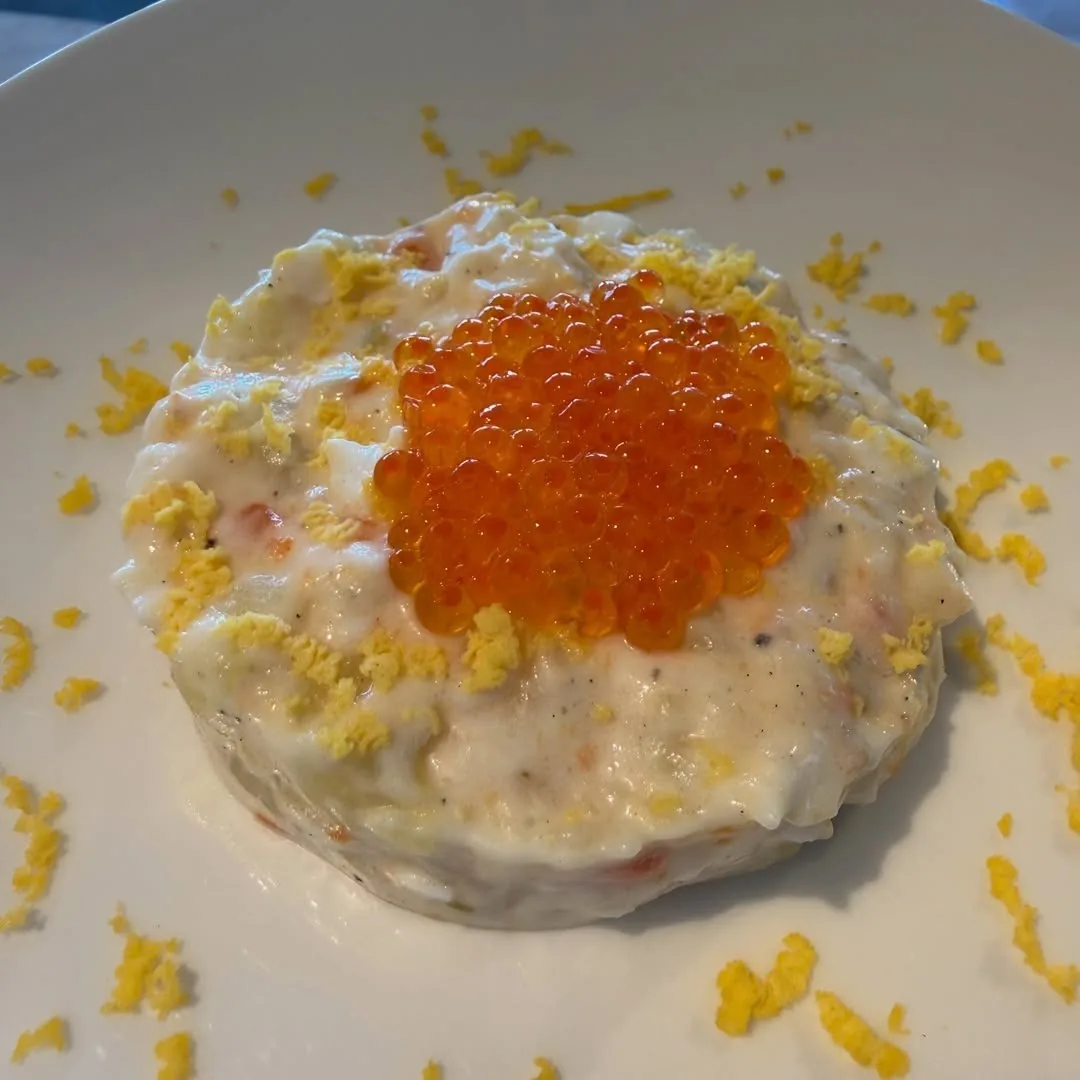 A round portion topped with orange fish roe on a white plate