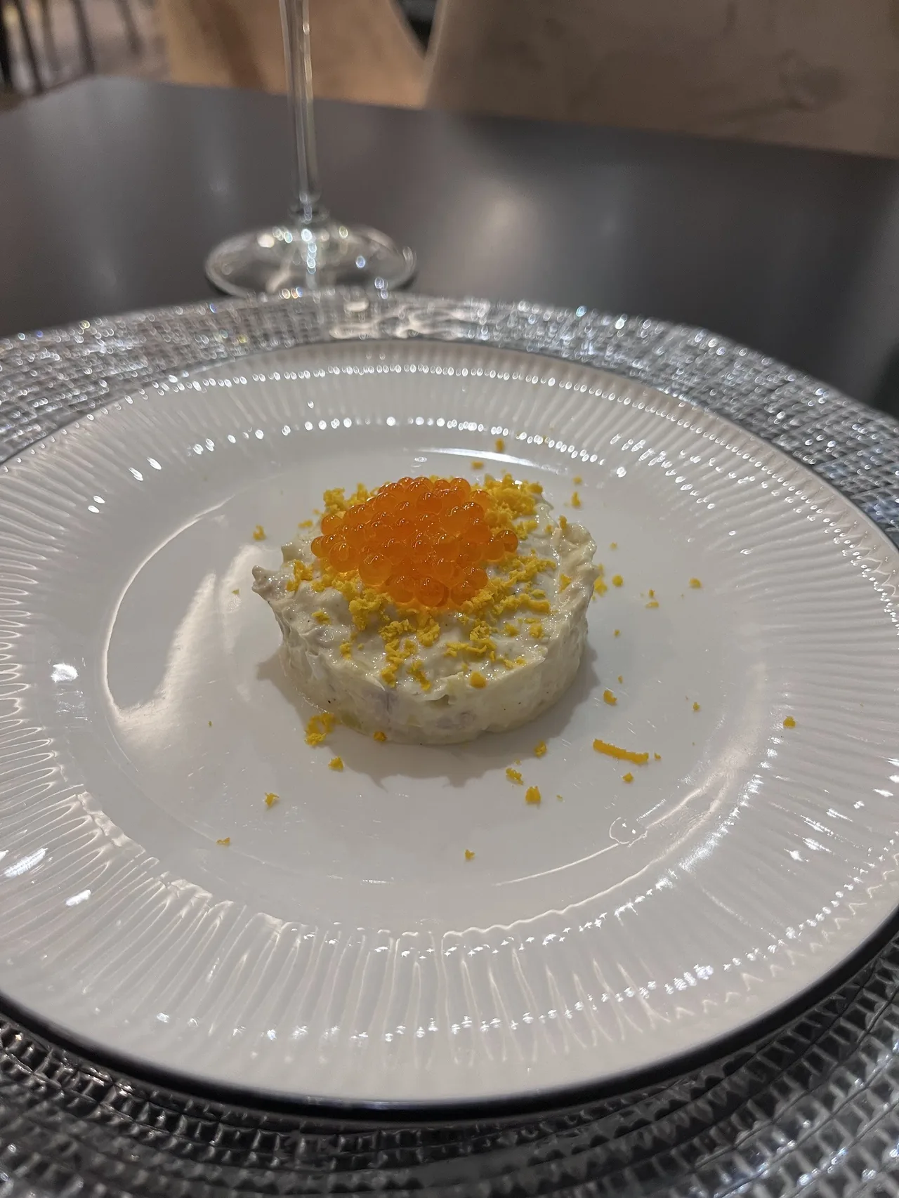 A round timbale topped with orange roe on a white plate