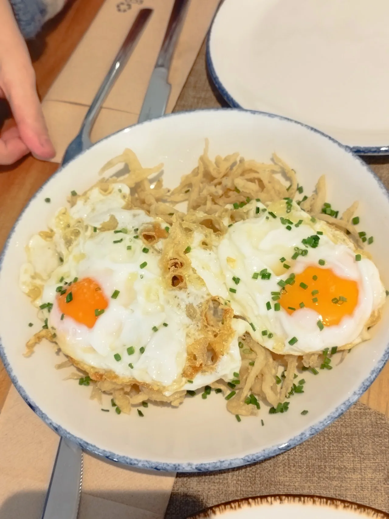 Two fried eggs over shredded fried potatoes on a plate