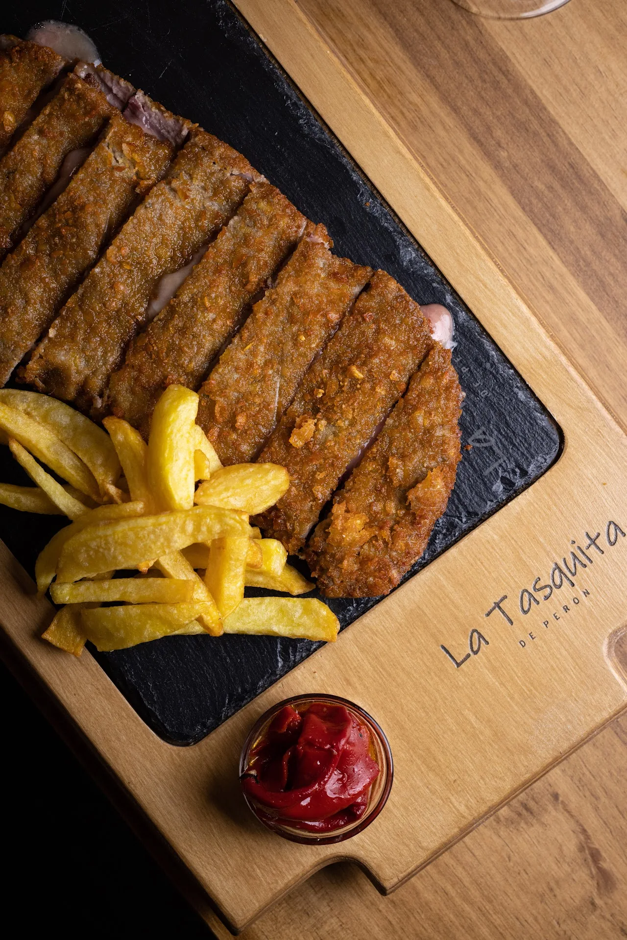 Breaded fried meat strips with french fries and a red dipping sauce