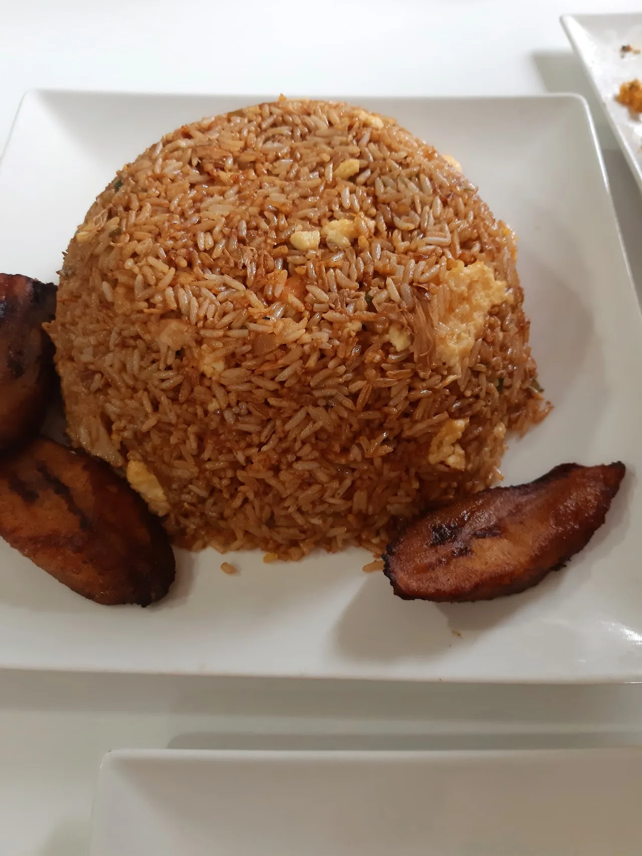 A mound of fried rice with grilled plantain slices