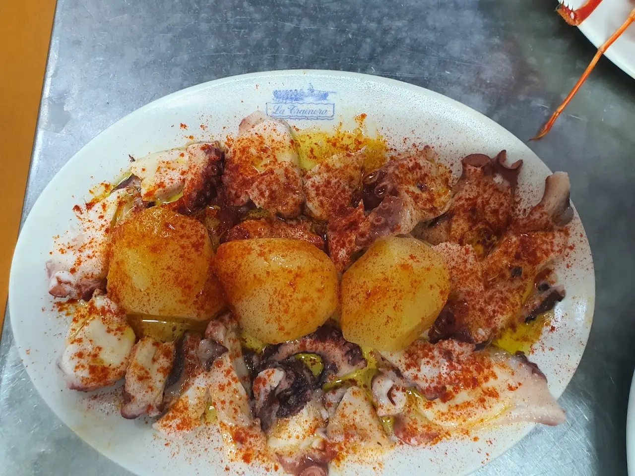 Grilled octopus and potatoes dusted with paprika on a white plate.