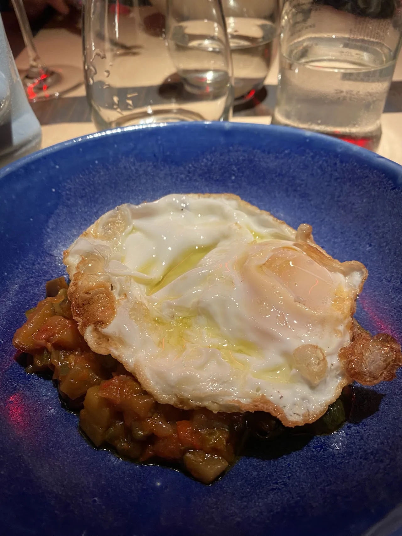 A fried egg over hash on a blue plate