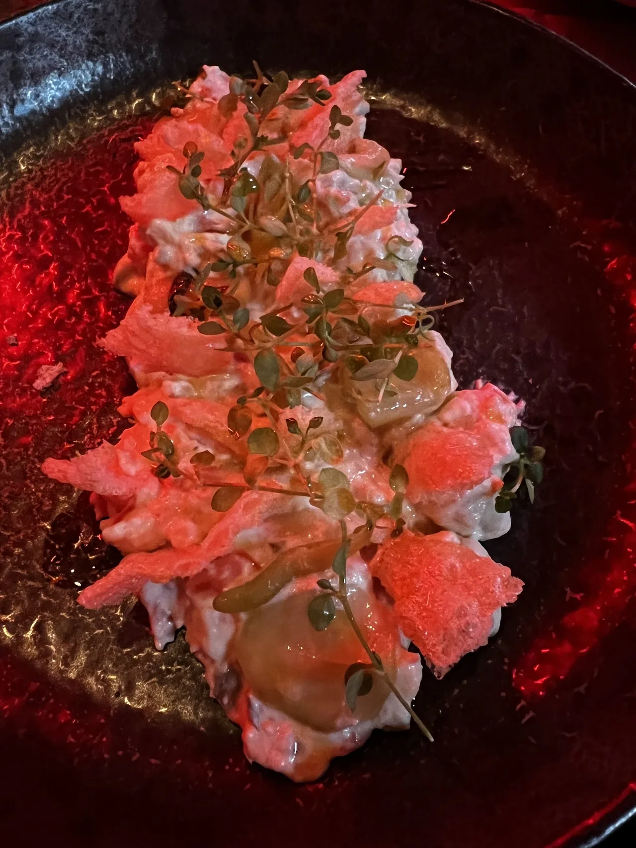 A tuna tartare with sauce, dotted plating on a dark plate