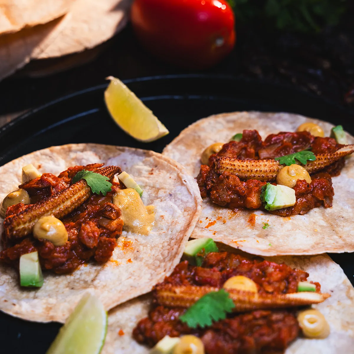 Corn tortilla tacos topped with meat, herbs, and pickled vegetables