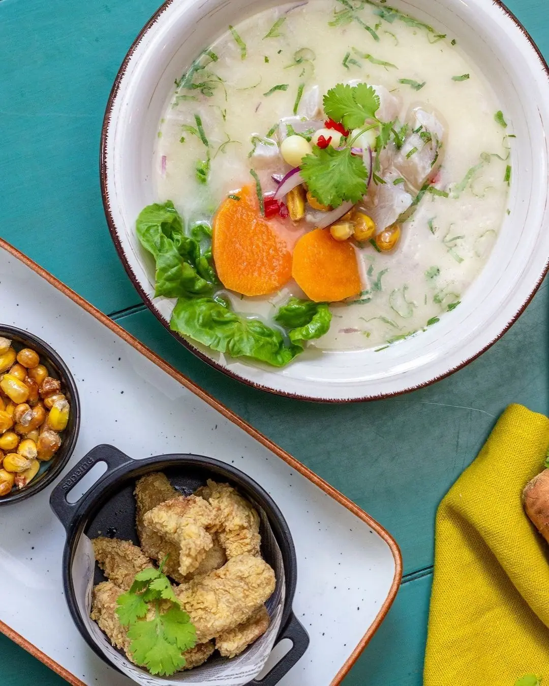 Peruvian ceviche in a creamy leche de tigre broth with sweet potato, corn, and crispy fried chicken bites on the side, La Turuleca