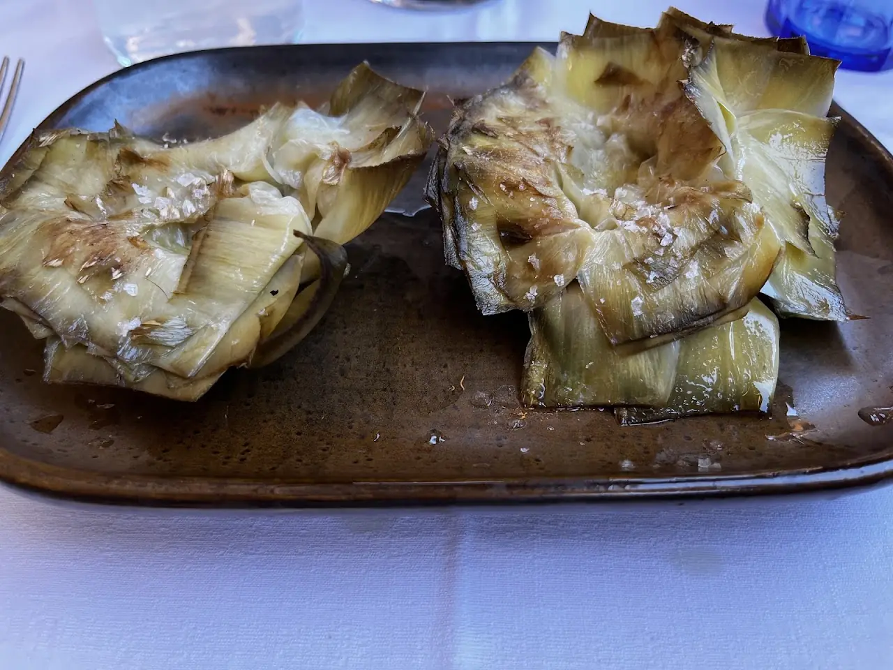 Grilled artichoke halves on a wooden board.