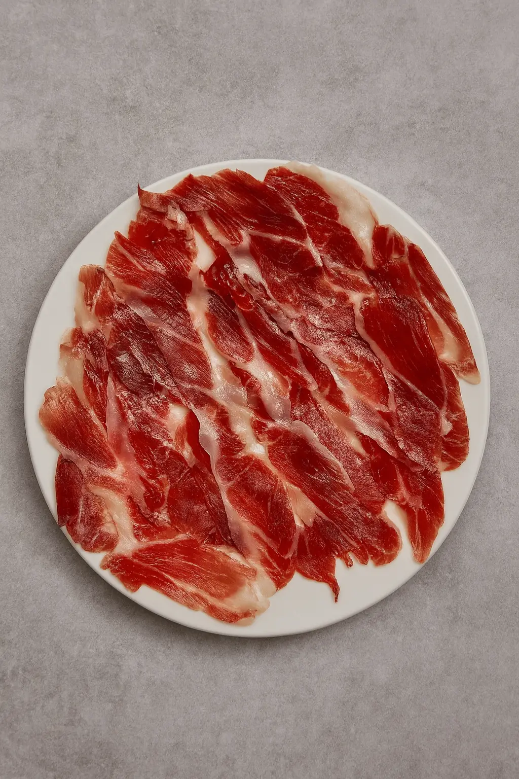 Thinly sliced cured ham arranged on a round white plate, La Yaya Amelia