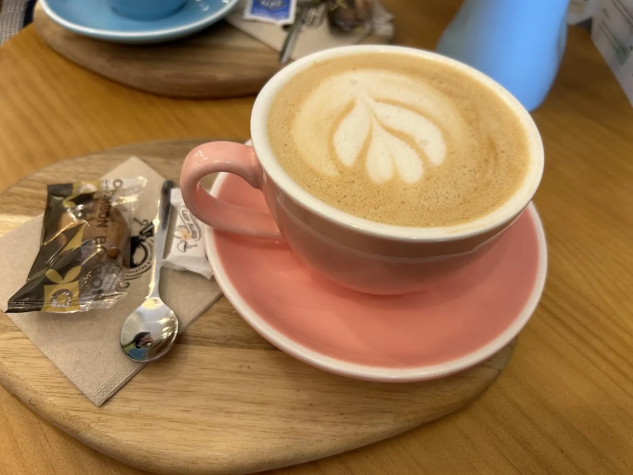 A latte with leaf-pattern latte art in a pink cup