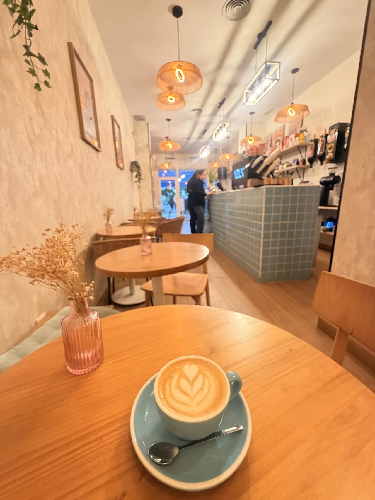 A latte with leaf-pattern latte art on a wooden table