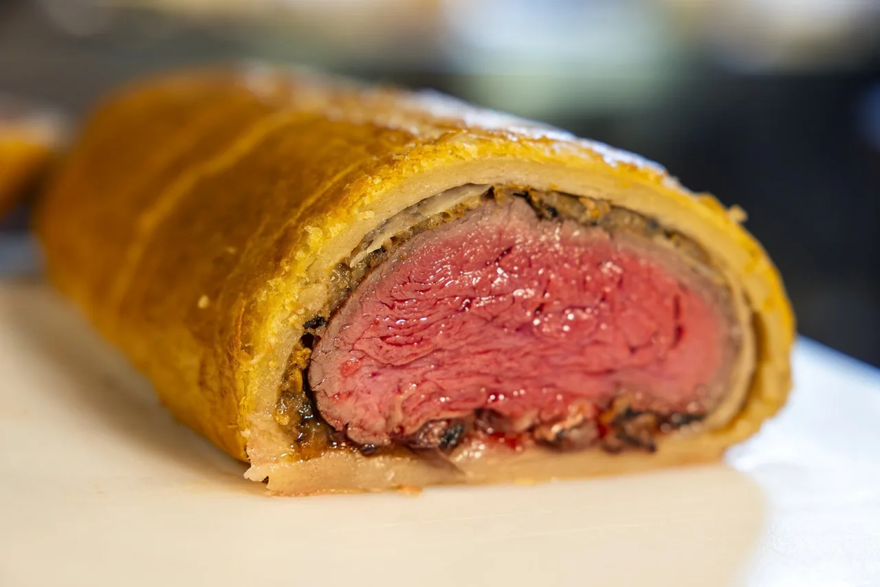 A cut pastry-wrapped roast with a pink centre on a plate