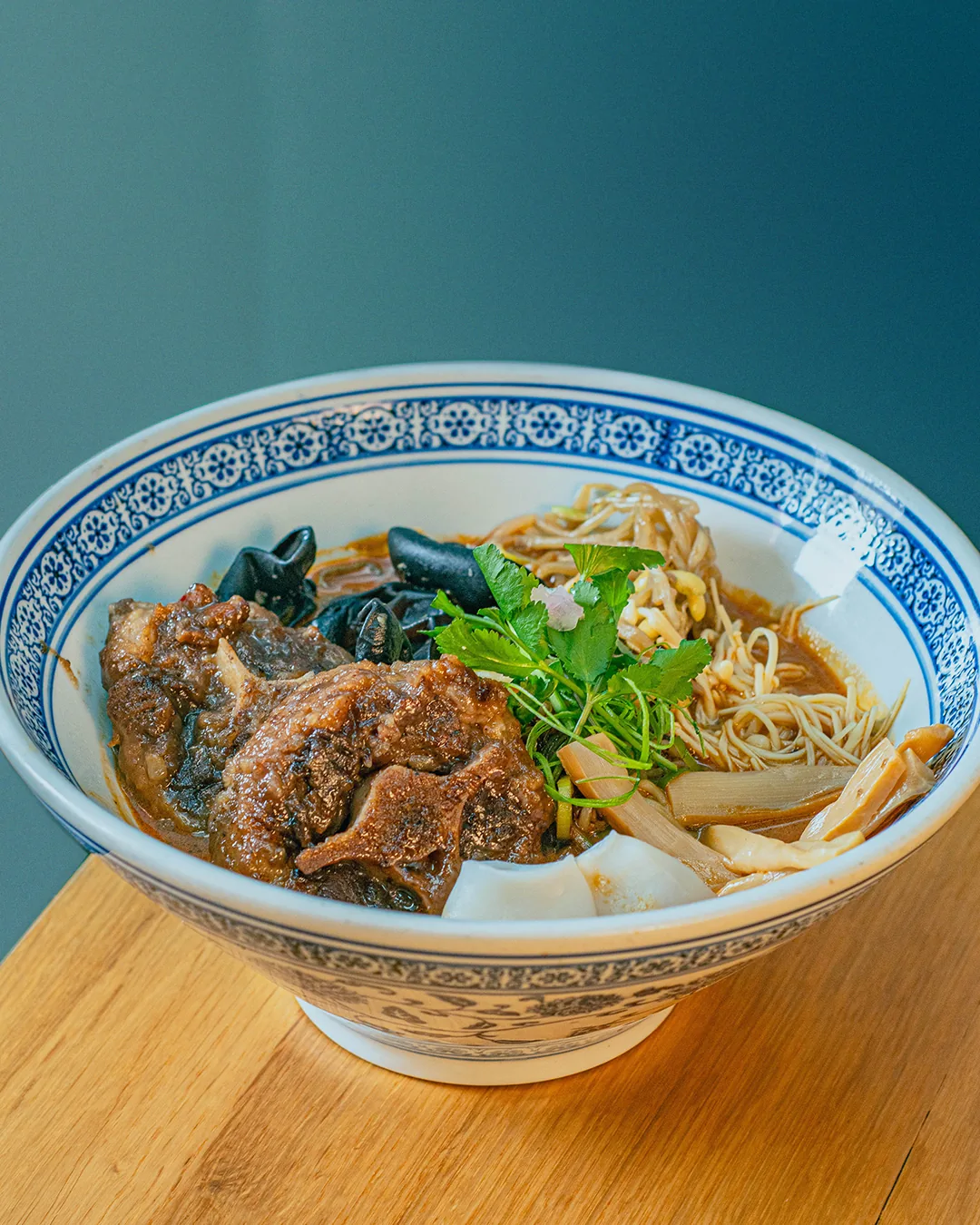 A bowl of hand-pulled noodle soup with sliced meat and herbs