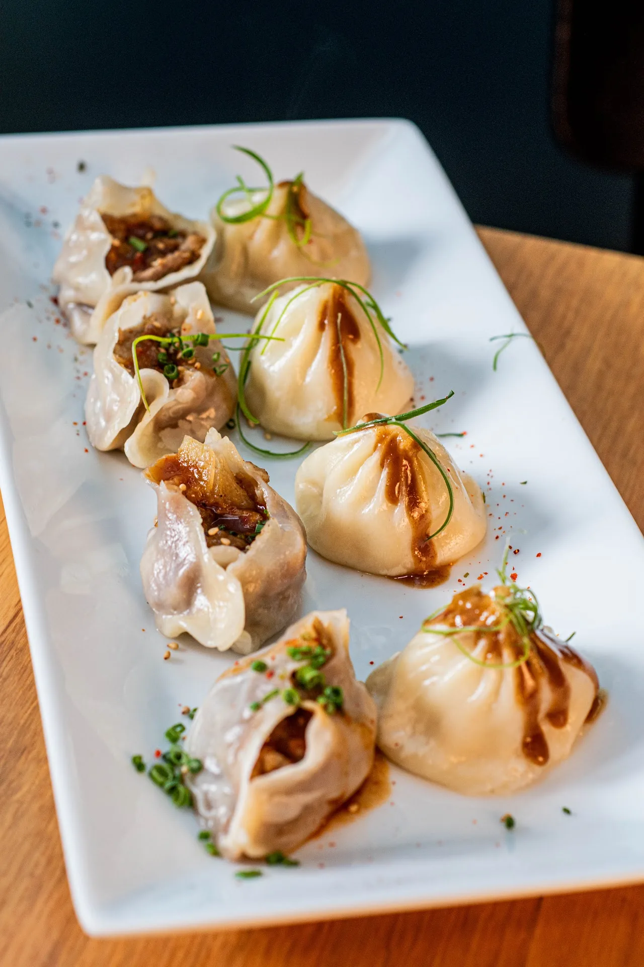 A plate of steamed dumplings with a sauce drizzle