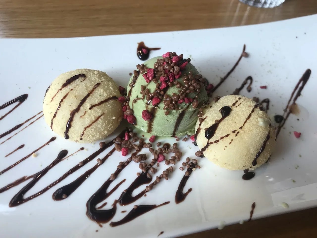 Three scoops of ice cream drizzled with chocolate sauce
