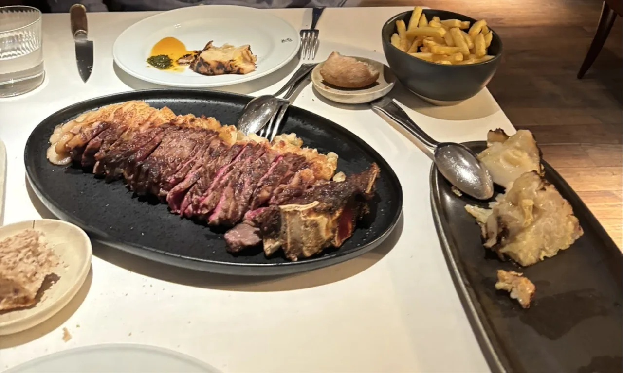 Sliced grilled steak on a dark oval plate at a set table