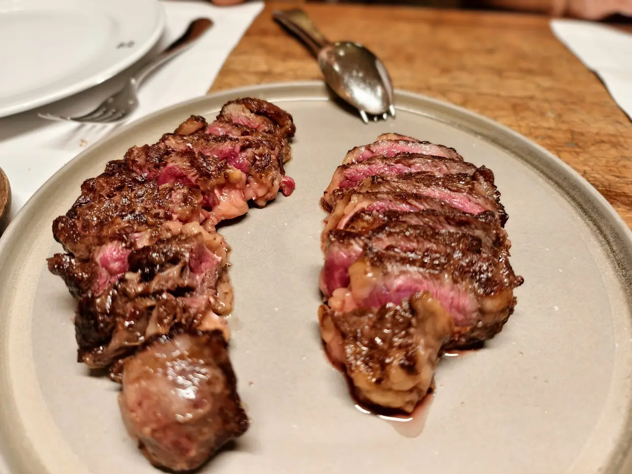 Two sliced grilled steaks plated, showing pink interior and charred crust