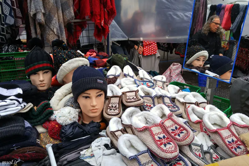 A market stall at El Rastro piled with knit slippers and hats displayed on mannequin heads