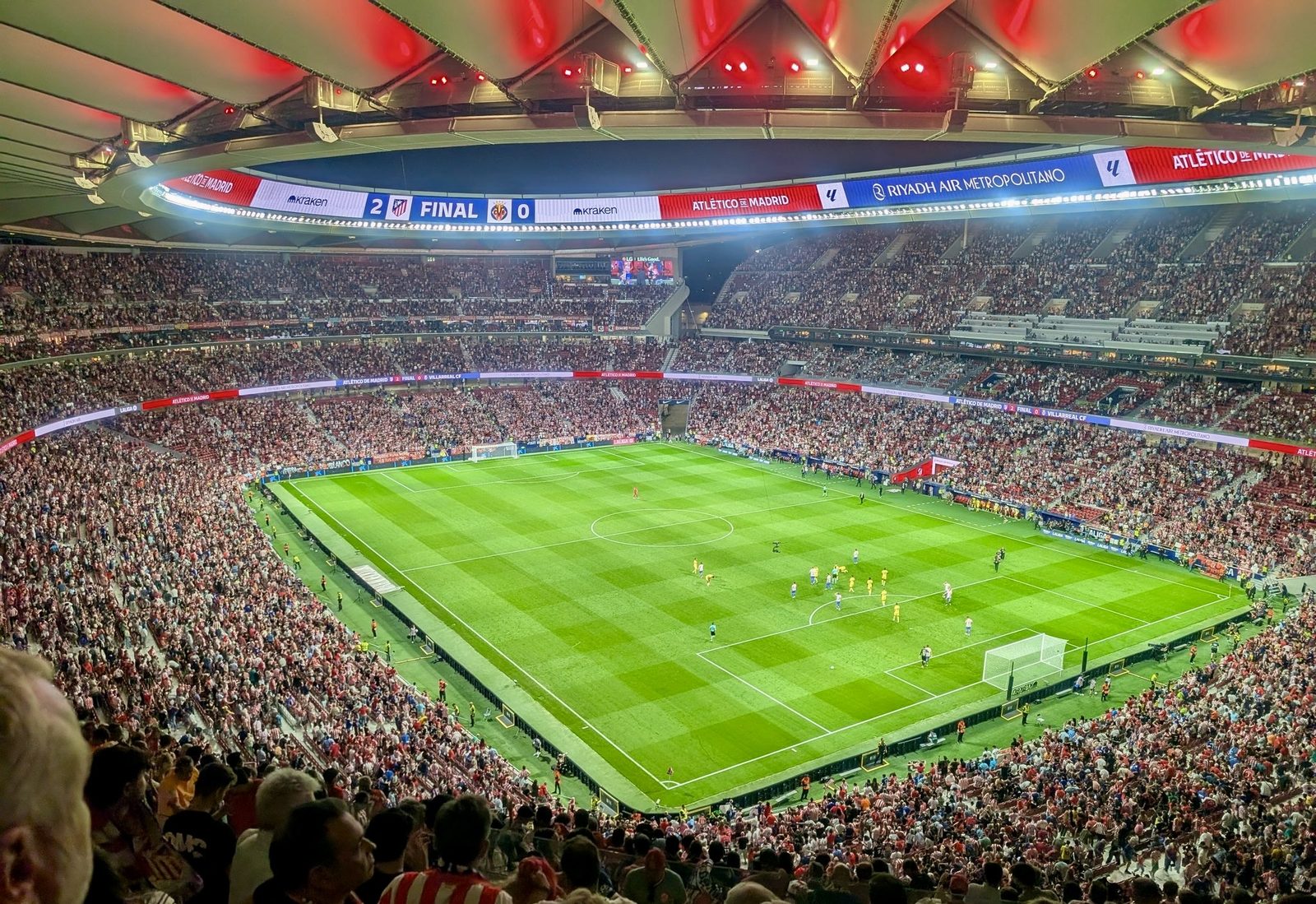 Interior of a packed Estadio Metropolitano during an Atlético de Madrid match, showing the pitch and stands under the stadium's canopy