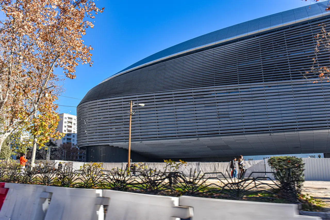 The curved, louvered metallic exterior of the renovated Santiago Bernabéu stadium against a clear sky