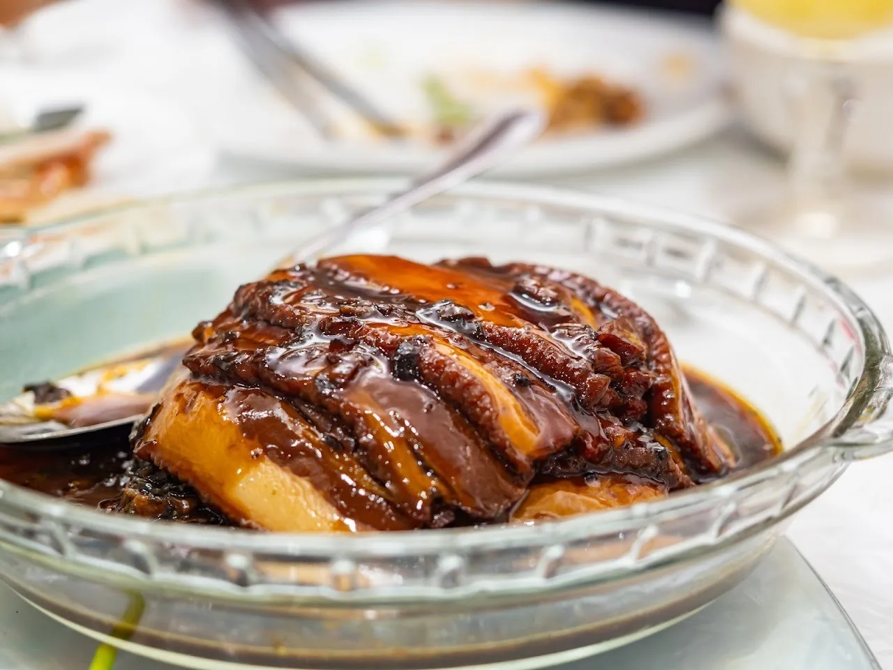 A glass bowl of glazed braised pork belly