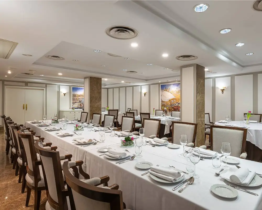 Formal dining room with a long table set for a group, upholstered chairs and framed wall art