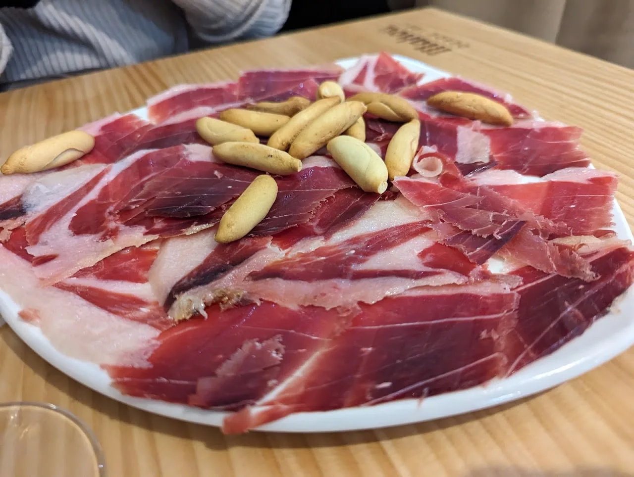 A plate of sliced Iberian ham with fried breadsticks