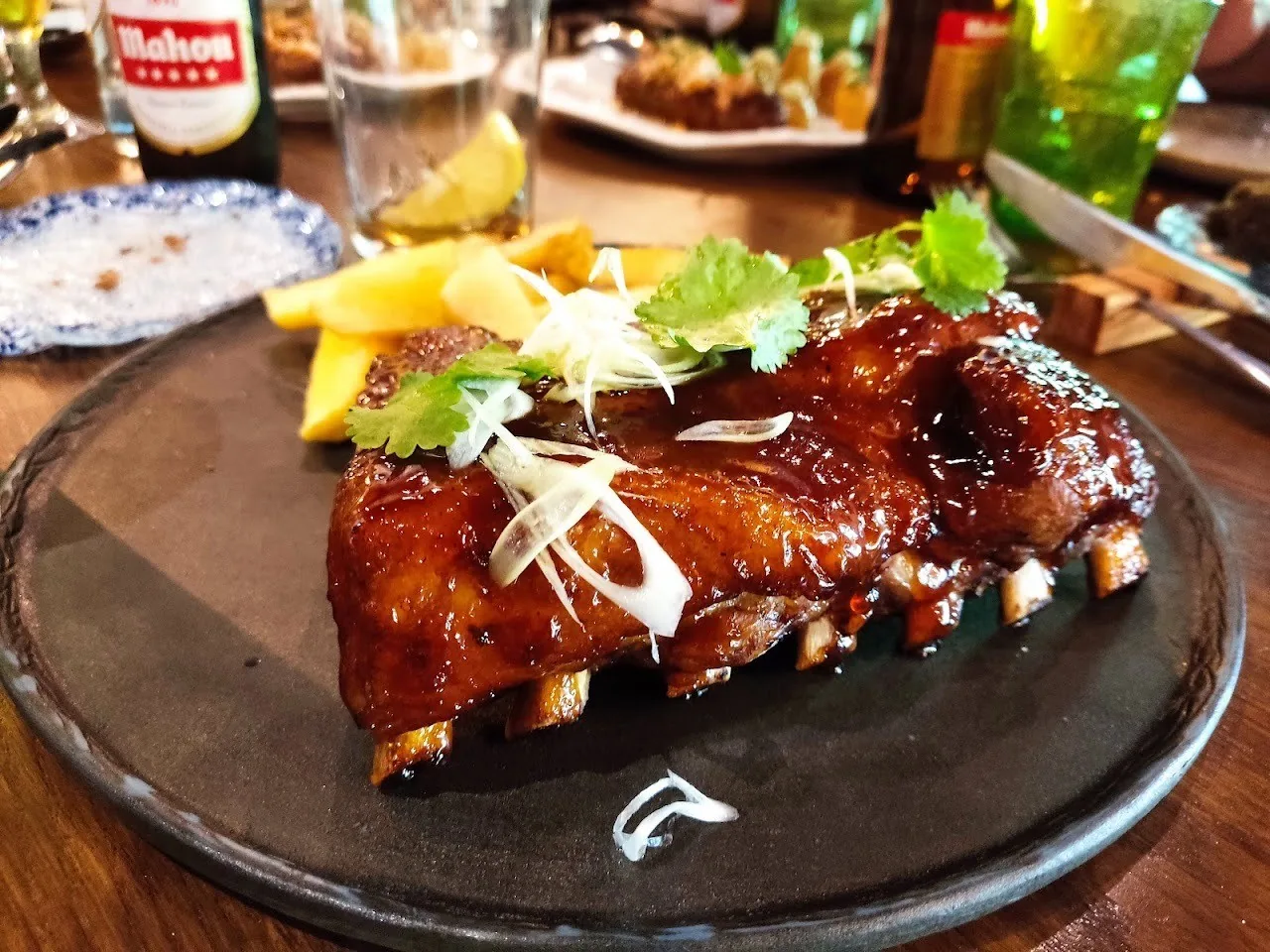 Glazed pork ribs with garnish on a dark plate