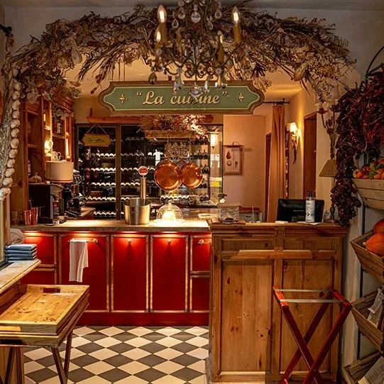 A wooden counter with red cabinets, shelves of bottles and a checkerboard floor