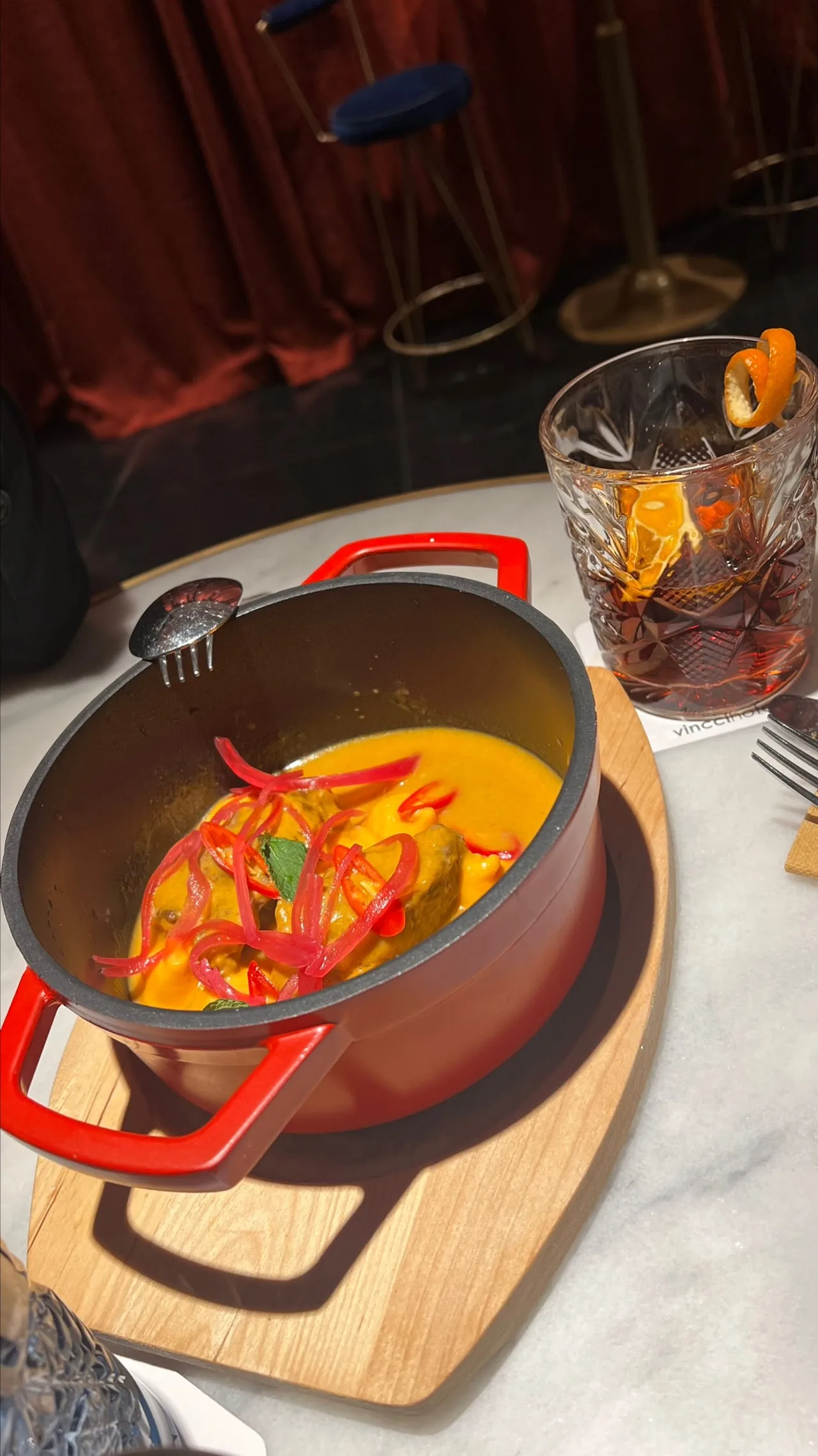 A pot of stew with tomatoes in orange broth