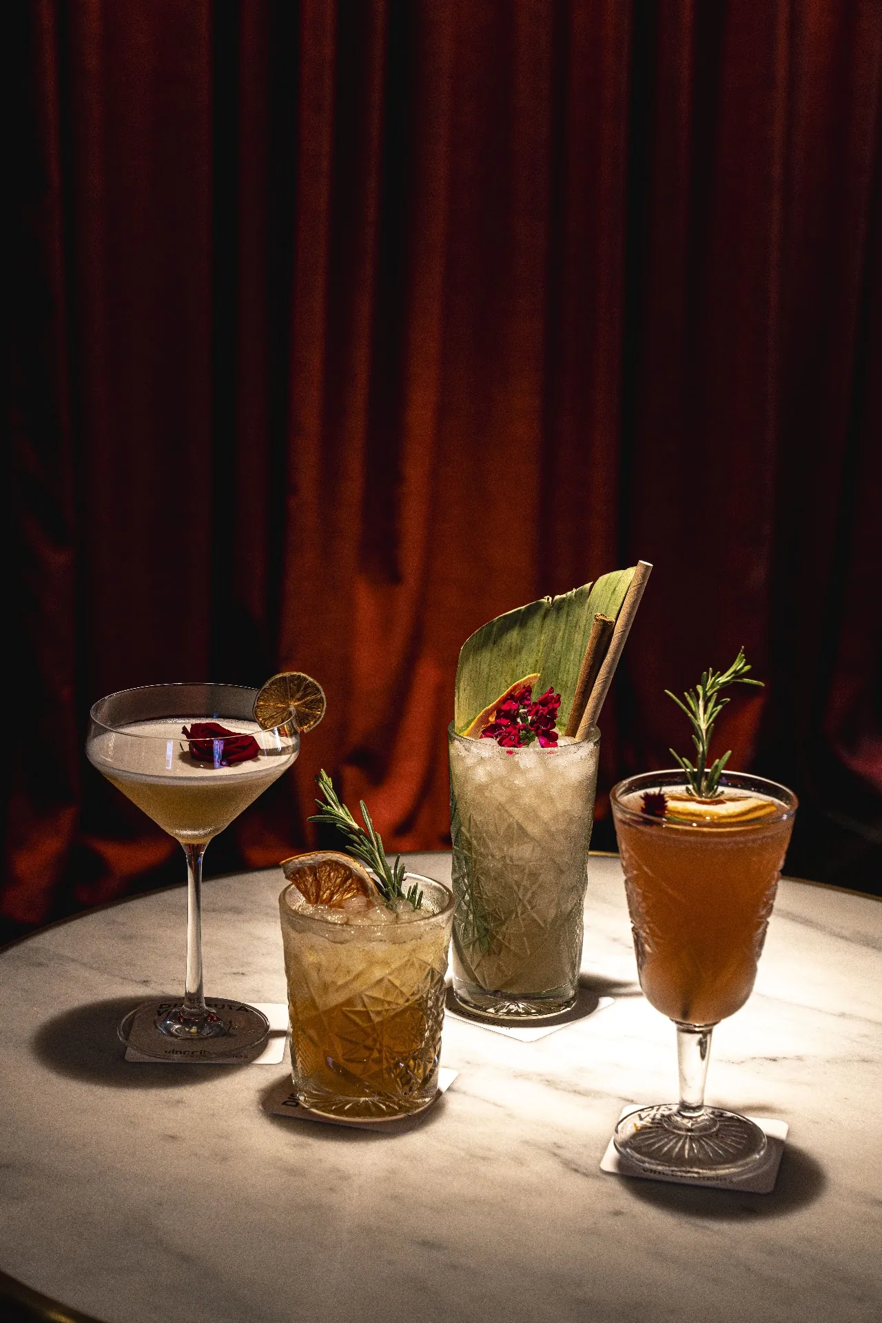 Three cocktails garnished with fruit and herbs