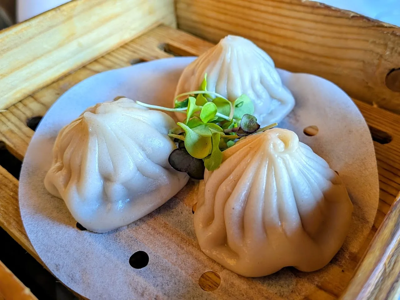 Three soup dumplings on a bamboo tray