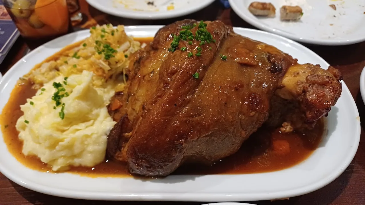 A roasted pork knuckle served with mashed potatoes and gravy