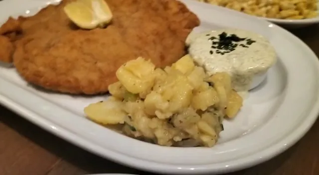 A breaded schnitzel with a side of potato salad