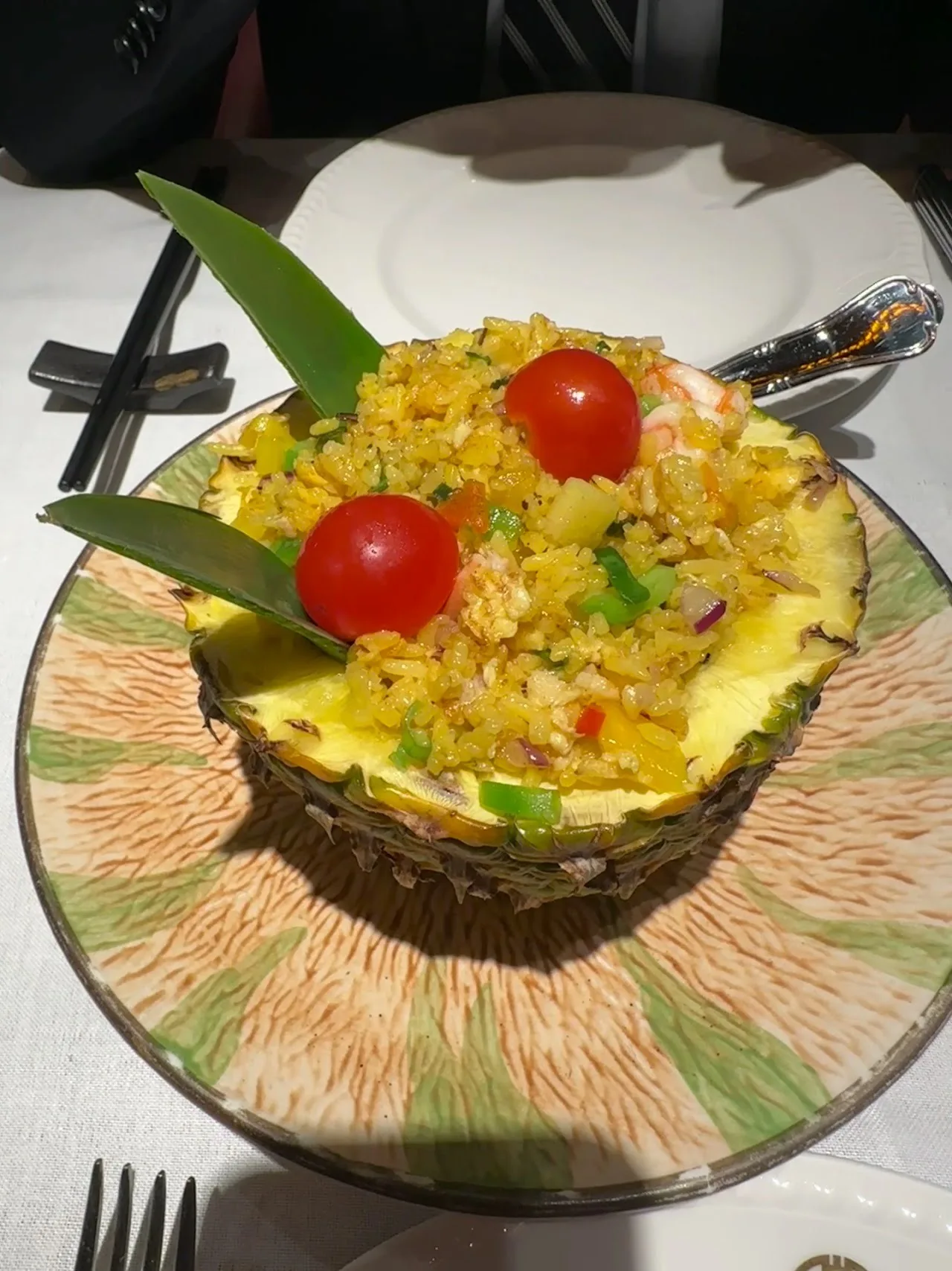 Fried rice served in a hollowed pineapple with tomato and herb garnish