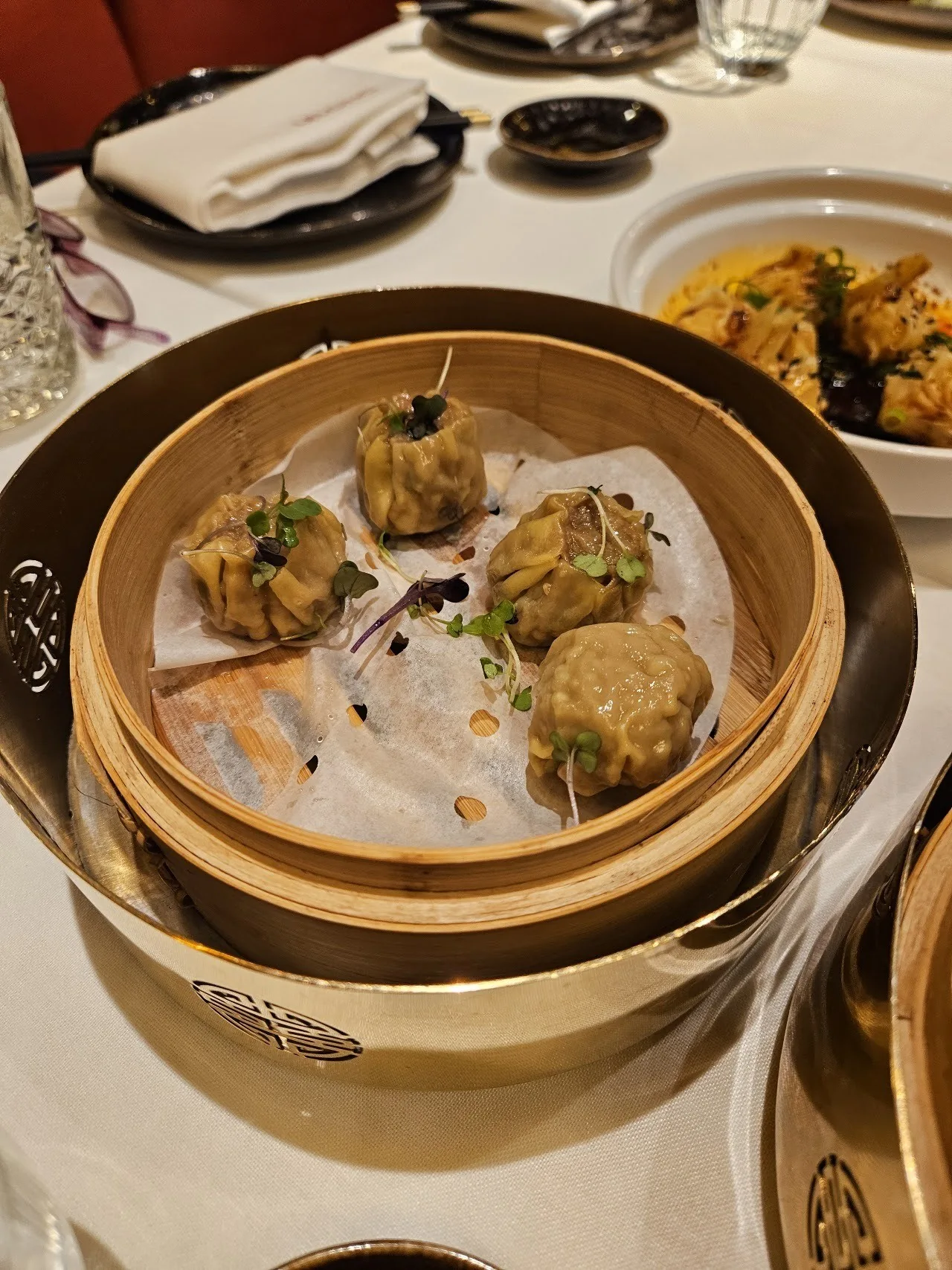 Bamboo steamers of dumplings on a table set with plates