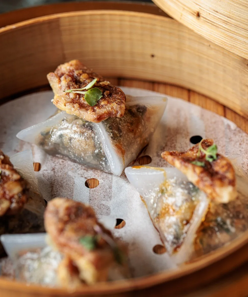 Pan-fried dumplings in a bamboo steamer lined with paper