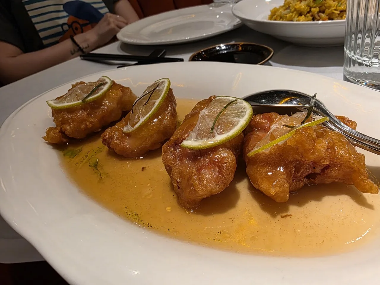 Fried chicken pieces with lime wedges in citrus sauce