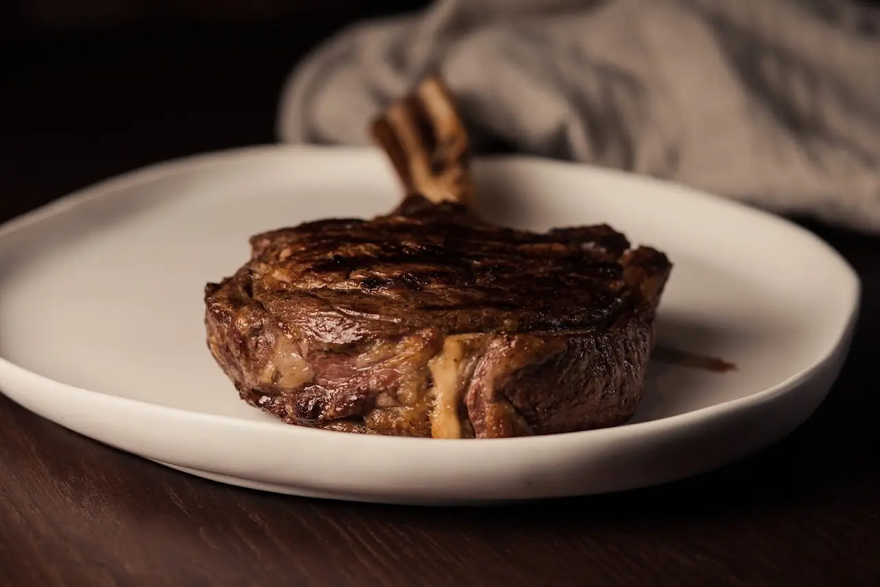 A grilled bone-in steak on a white plate