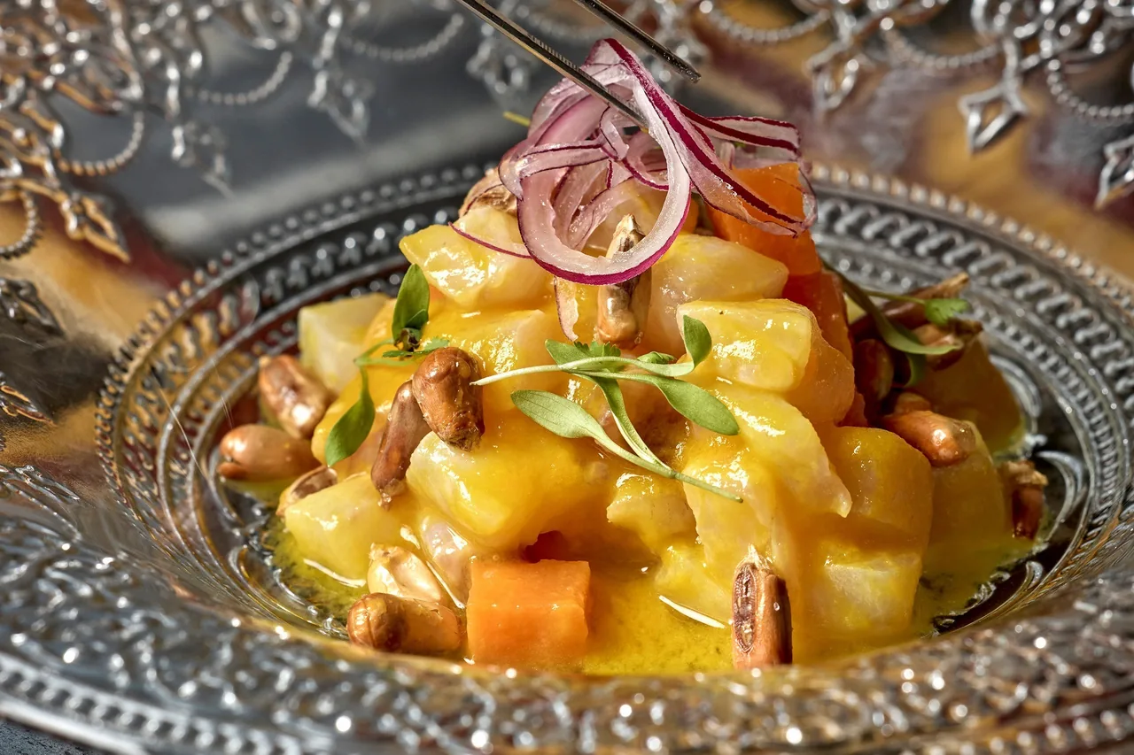 A plate of diced potatoes in a golden sauce with a garnish on top