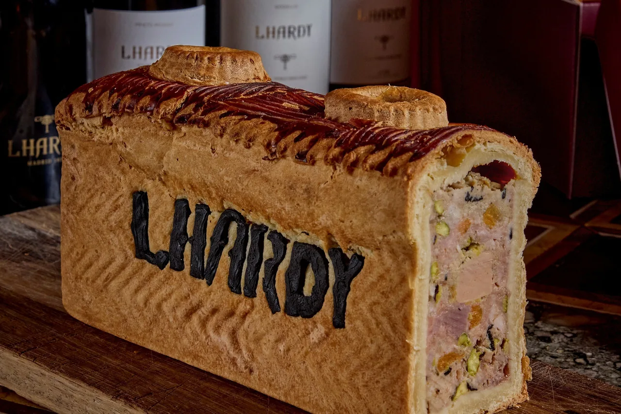 A loaf-shaped pastry crust with the name pressed into the side, cut to show the filling