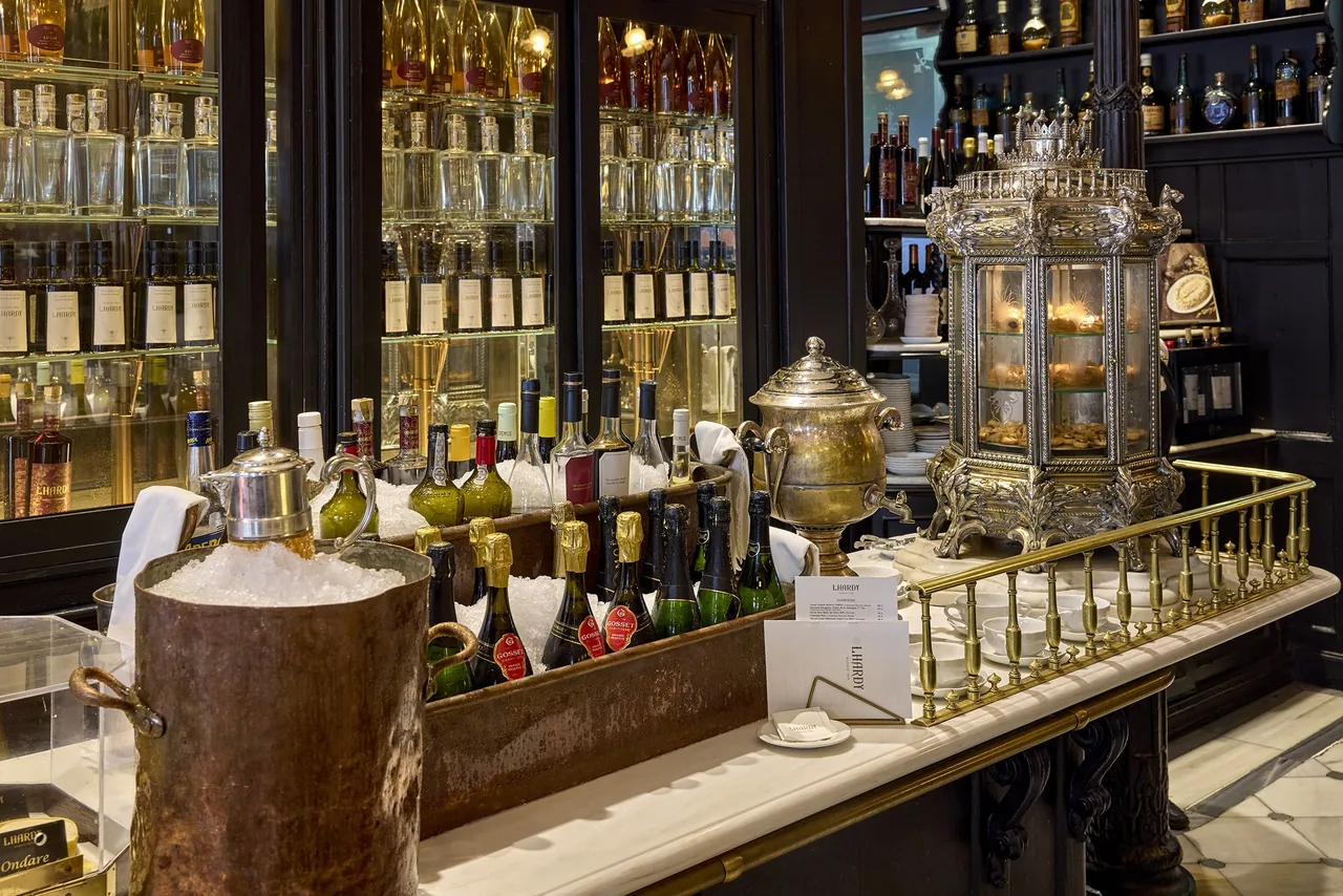 A long counter with an ornate silver samovar and shelves of bottles behind it