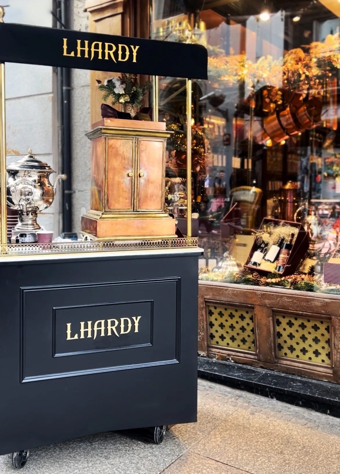 A dark wooden counter with a copper samovar beside a shop window